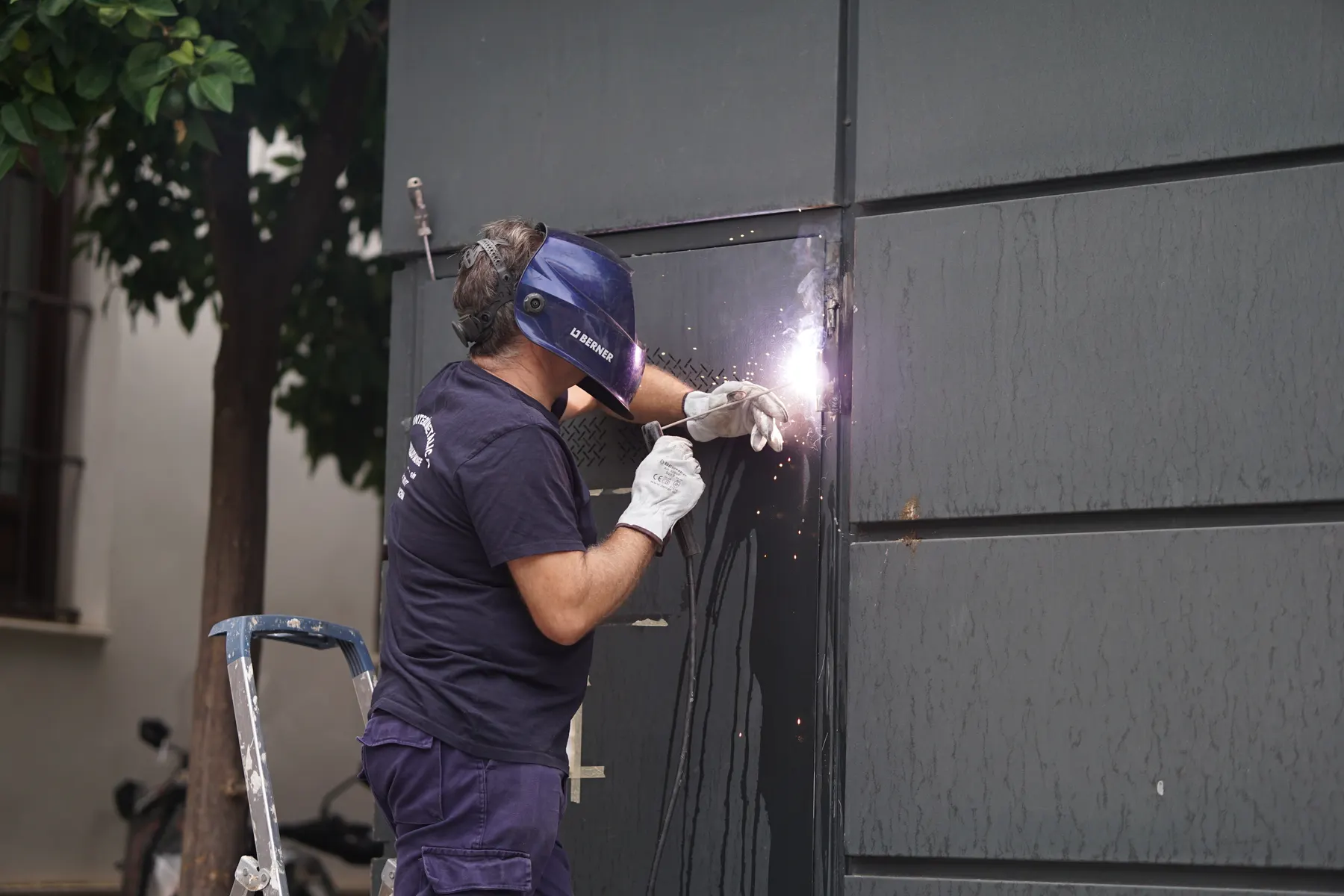 A tradesperson in protective gear working on a metal frame at a job site